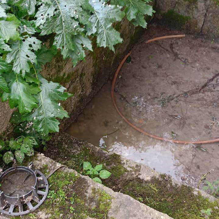 Achique del agua rebosada por un atasco en el suelo de una vivienda de Noia