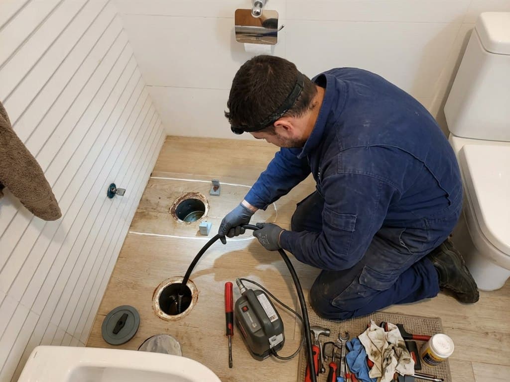 Operario de Net & Clair Barbanza S.L.U. desatascando el saneamiento del baño de una vivienda en el Barbanza