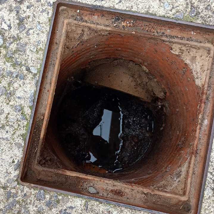 Arqueta de saneamiento abierta en la calle antes de la limpieza