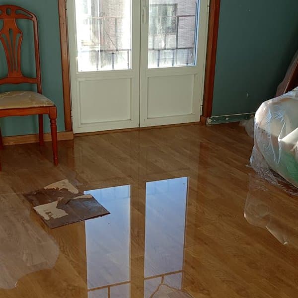 Suelo de parqué encharcado tras una inundación en una vivienda de Noia