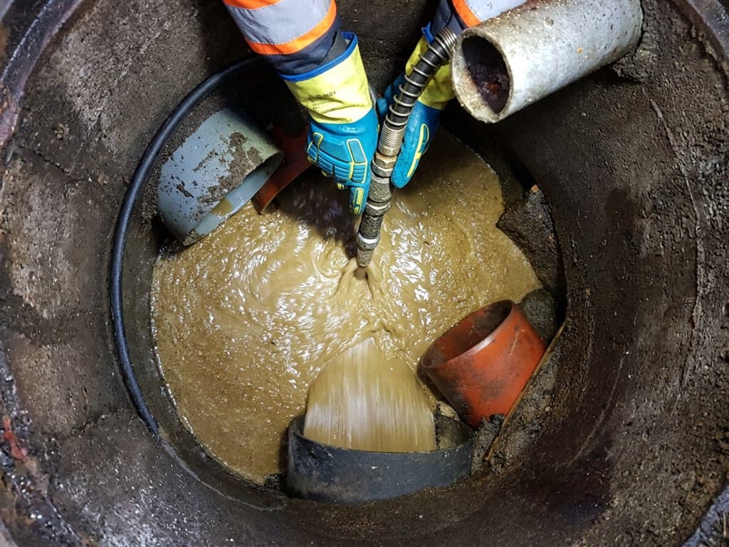 Operario de Net & Clair Barbanza S.L.U. desatascando con sonda el interior de una arqueta de saneamiento
